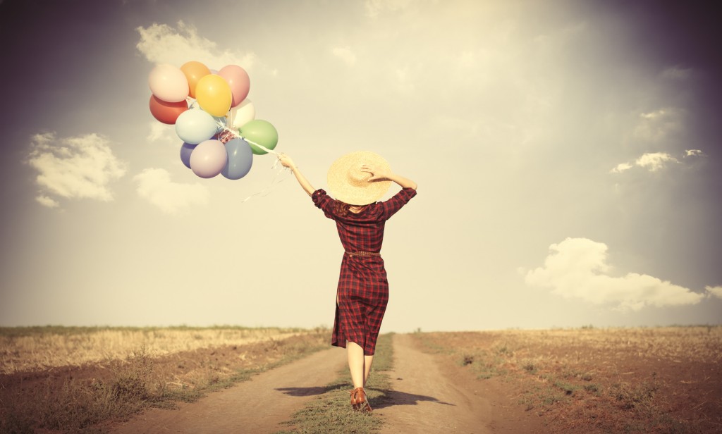 girl with multicolored balloons and bag